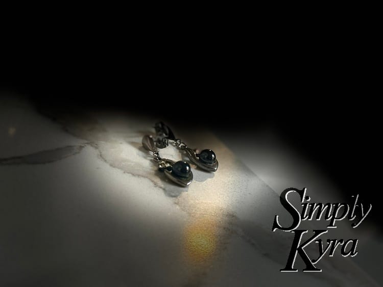 Image shows the earrings under a spotlight with a black background. 