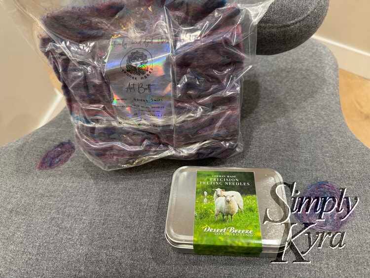 Image shows the newly patched spots, the bag of wool roving, and the closed felting needle container. 