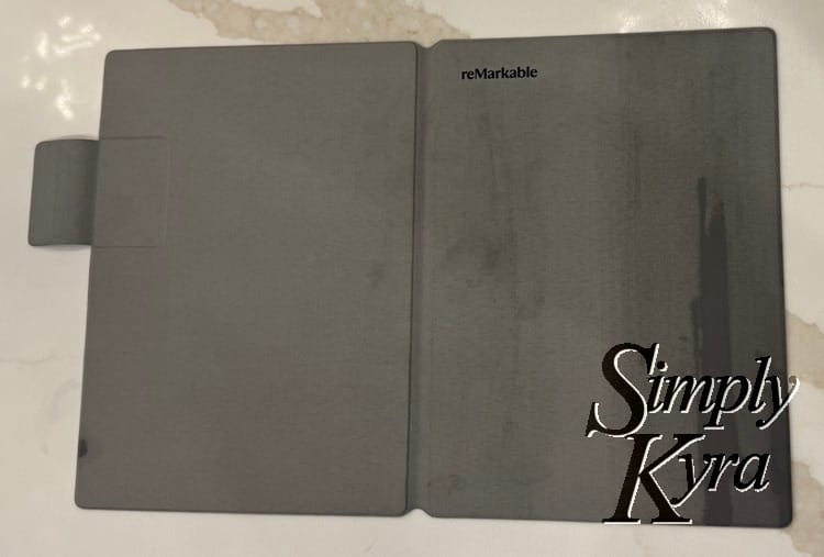 Image shows the reMarkable cover opened flat with the back and front facing up and streaks on the right side showing where it's wet and where my wet hands touched it. 
