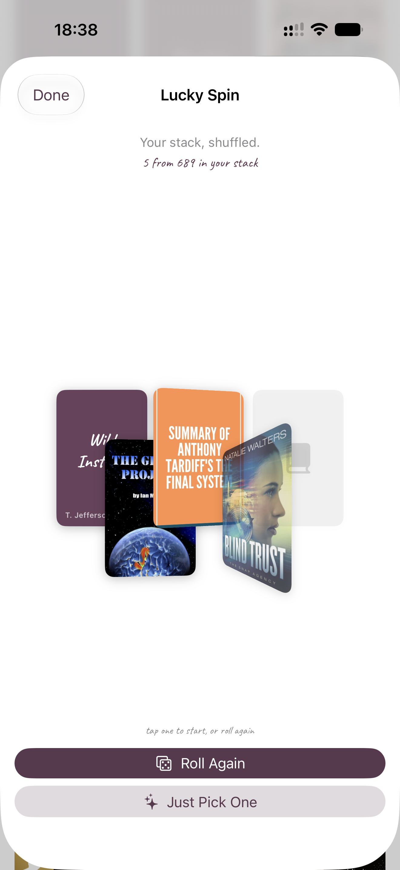 Phone screen showing five fanned book cover cards under the heading Lucky Spin, with Roll Again and Just Pick One buttons below.