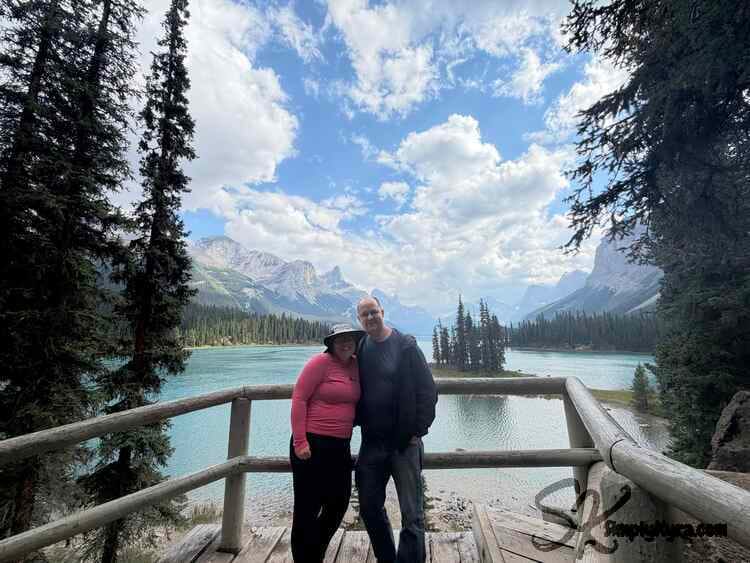Me and my husband leaning into each other as we pose in front of the guardrail overlooking Spirit Island. 