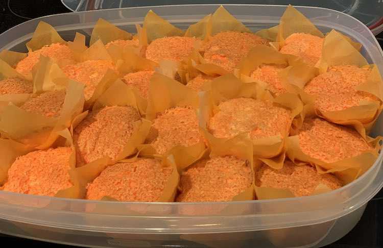 A oval container filled with finished cupcakes.