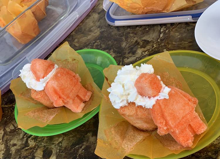 Two plates with a cupcake on each with white whip cream and a large sugar LEGO® figure leaned against each.