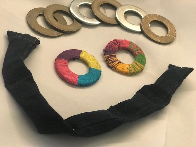 The wiggle weight is curved along the bottom of the picture. The two embroidered washers are in the middle and the plain washers and spread across the top.