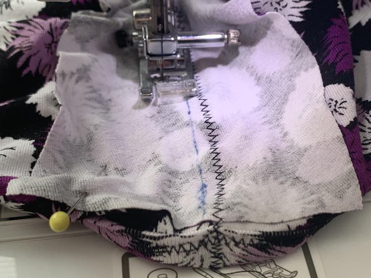 The dress is currently in the sewing machine and has been stitched fully on the one side of the placket and halfway up the other side. The unstitched side still has a yellow pin holding the fabric in place. 