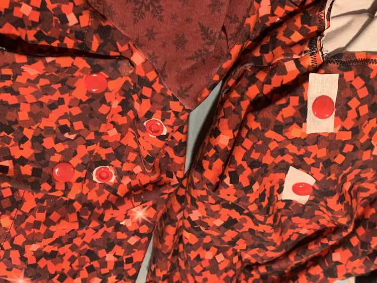 Both hoods are shown with the new KAMsnaps showing. The hood to the left shows the interfacing trimmed around the snap so there's only a little border of white. The hood on the right shows the square or rectangular patches of interfacing before it was trimmed smaller.