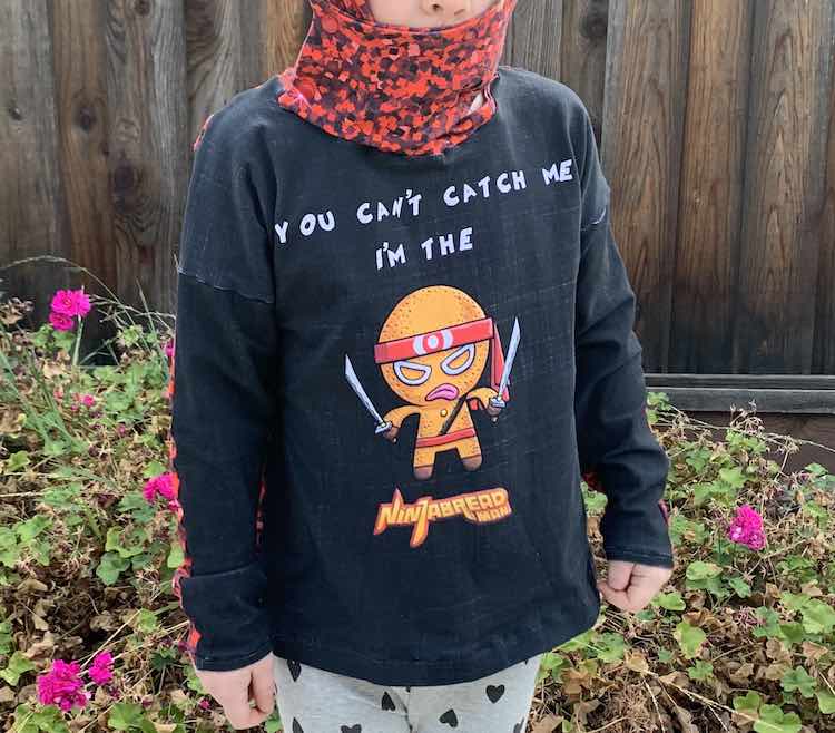 Closeup of Ada's Ninjabread Man top. At the top of the photo you can see the hood flap snapped to the main hood keeping Ada's mouth easily covered.