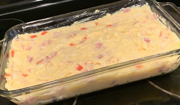 Closeup of a glass casserole dish containing the flattened mixture.