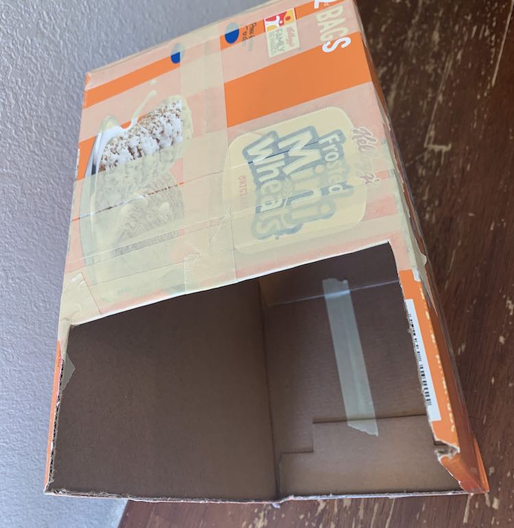 View from above showing the box. You can see the taped top of the box and the inside. The very bottom shows a strip of tape going from one inner flap to the other inner flap.