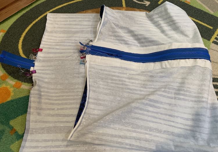 the pillow case is inside out and folded in half so you see the fabric side on the left and the zipper side, folded up, on the right. Both sides are clipped on and around the zipper.