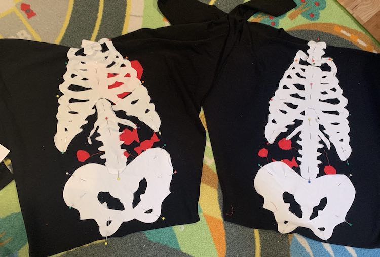 Image shows the front (left) and back (right) of the sweater laid out side by side. The front has a red heart sewn on while both have candies sewn on. They both have white knit neck, ribs, spine, and pelvic bone pinned on. 