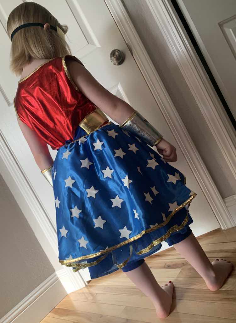 View of the back of the outfit. The blue leggings are, again, poking out from below the skirt and the skirt overlay hides the skirt itself, from the back.