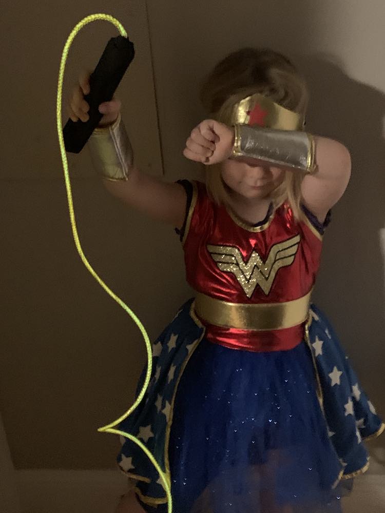 Image from above of Ada, as Wonder Woman, holding up the glowing lasso of truth, while blocking her face from attacks.