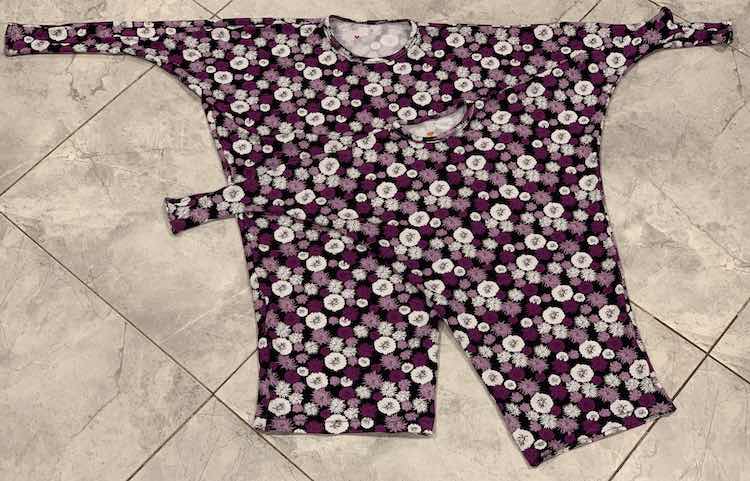 Image shows a flat lay of the two finished flowered tunics laying on the kitchen floor. Inside the neckline you can see, if you look closely, a little red or orange heart on the white-ish inside.