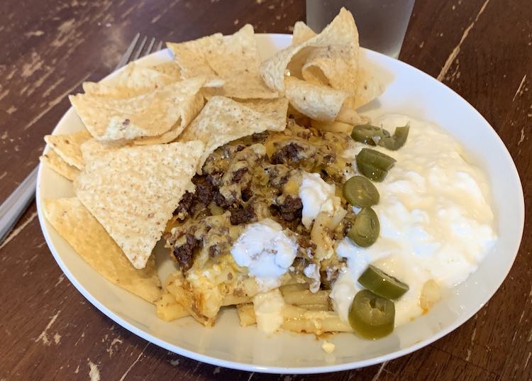 Image shows a closeup of my plate filled with the taco lasagna-ish, tortilla chips, yogurt, and a row of sliced jalapenos.
