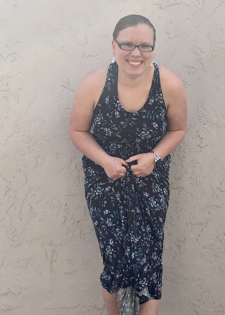 Image shows me wearing the lightweight cotton spandex blend Brazi dress as I lean forward and gather it up in my hands.