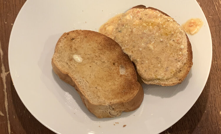 Two plain pieces of bread that have been soaked with the leftover tomato oil.