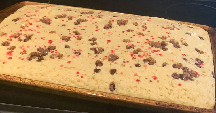 Image shows the pan horizontally with brown caramel lumps and dots of red and pink all over. 