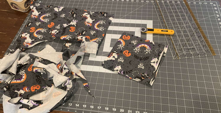 Image shows a large scrap of fabric with Halloween unicorns and unicorn kitties, and unicorn pumpkins along with bats, skulls, and rainbows.