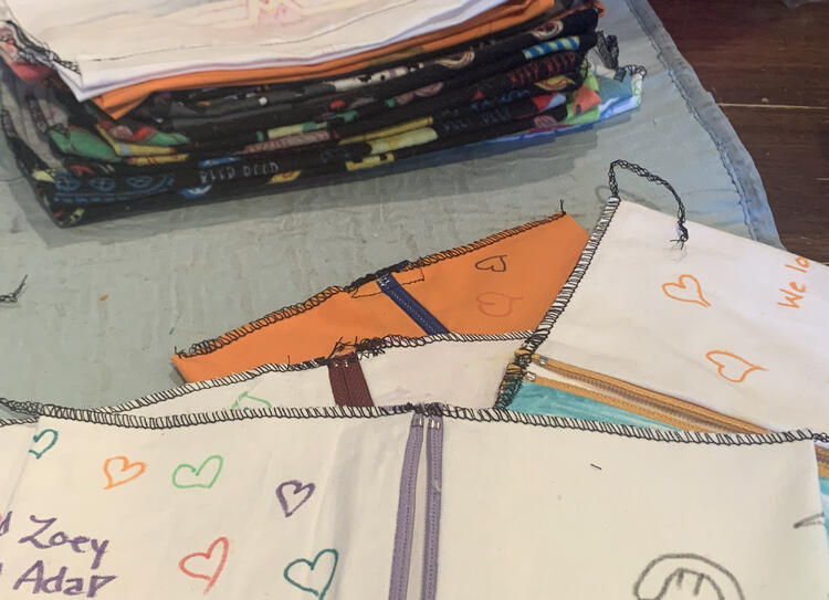 Image shows a staggered stack of inside out pouches showing one of their zipper ends. In the background is a stack of flat cinch pouches that I was working on at the same time.