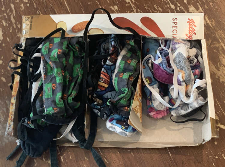 Image shows a bent cereal box that's open in the top and side with three sections containing wrinkled masks.