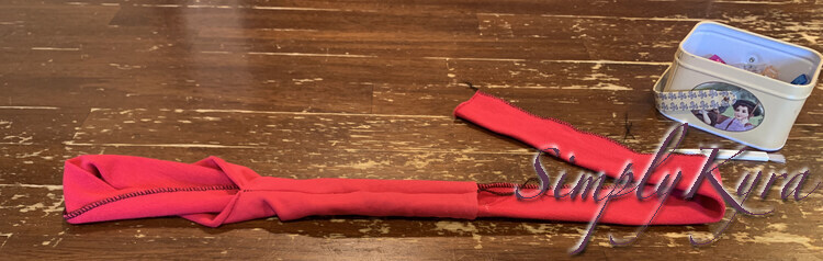 Image shows the band folded in half with the longer end going through the opening and out then other end. 