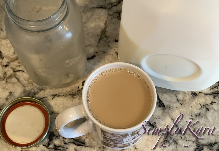 My mug is filled with light brown liquid. Behind it sits an empty canning jar, the upside down lid, and a jug of milk. 
