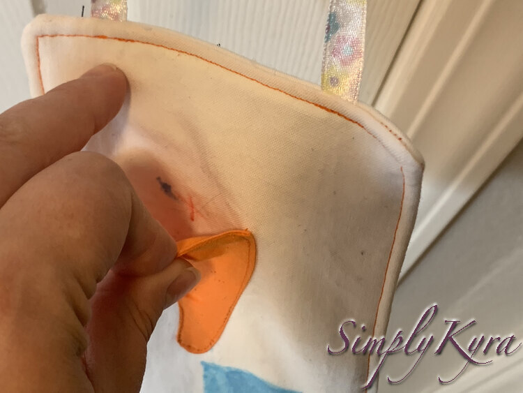Closeup of the front of Zoey's tooth fairy hanging showing the x inside the orange tooth pocket.