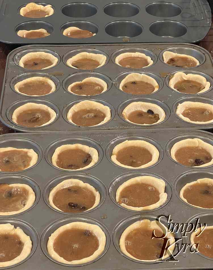 Image shows just over two muffin tins each filled with a pastry hollow muffin filled with brown liquid with the odd bubble or brown (raising) lump.