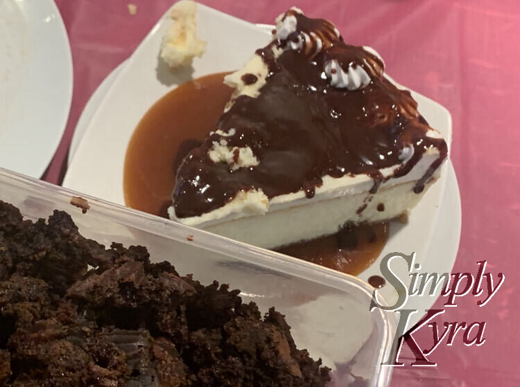 Image is the same as above but this time the container of brownie bits are held slightly in front of the cheesecake blurring the background a tad.