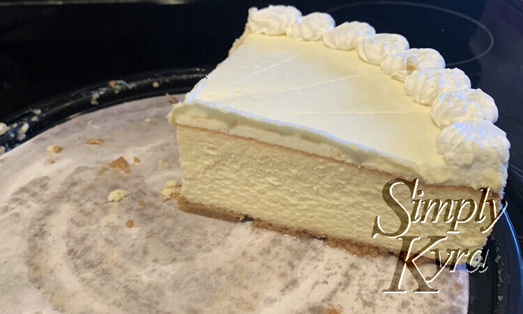 Image shows four slices of cheesecake still unsliced on a large cardboard cheesecake base from Costco.