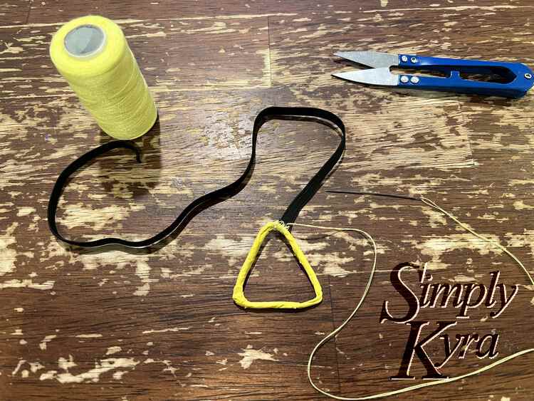 image shows the one end of the elastic to the top right side. It is secure but the thread still needs to be tied off as it's still coming from the spot.