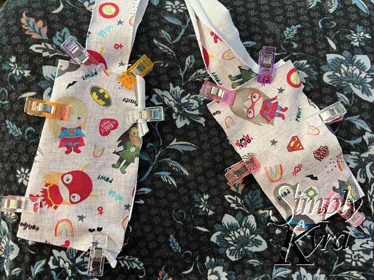 Image shows the rectangular part of the luggage tags laid out side by side with the strap coming out the top. There are clips around the outside holding them together.