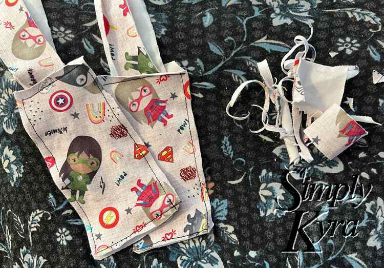 Image shows the two tags looking bit more put together with straight edges next to the stitches. They stacked overlapping to the left with the right side of the image shows the trimmed away pieces.