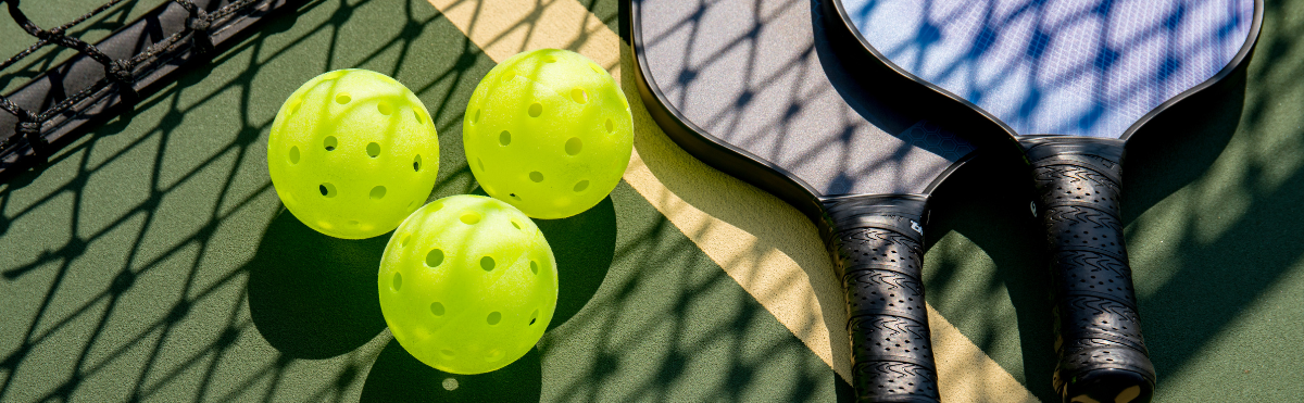 Two paddles and 3 pickleballs, waiting to go