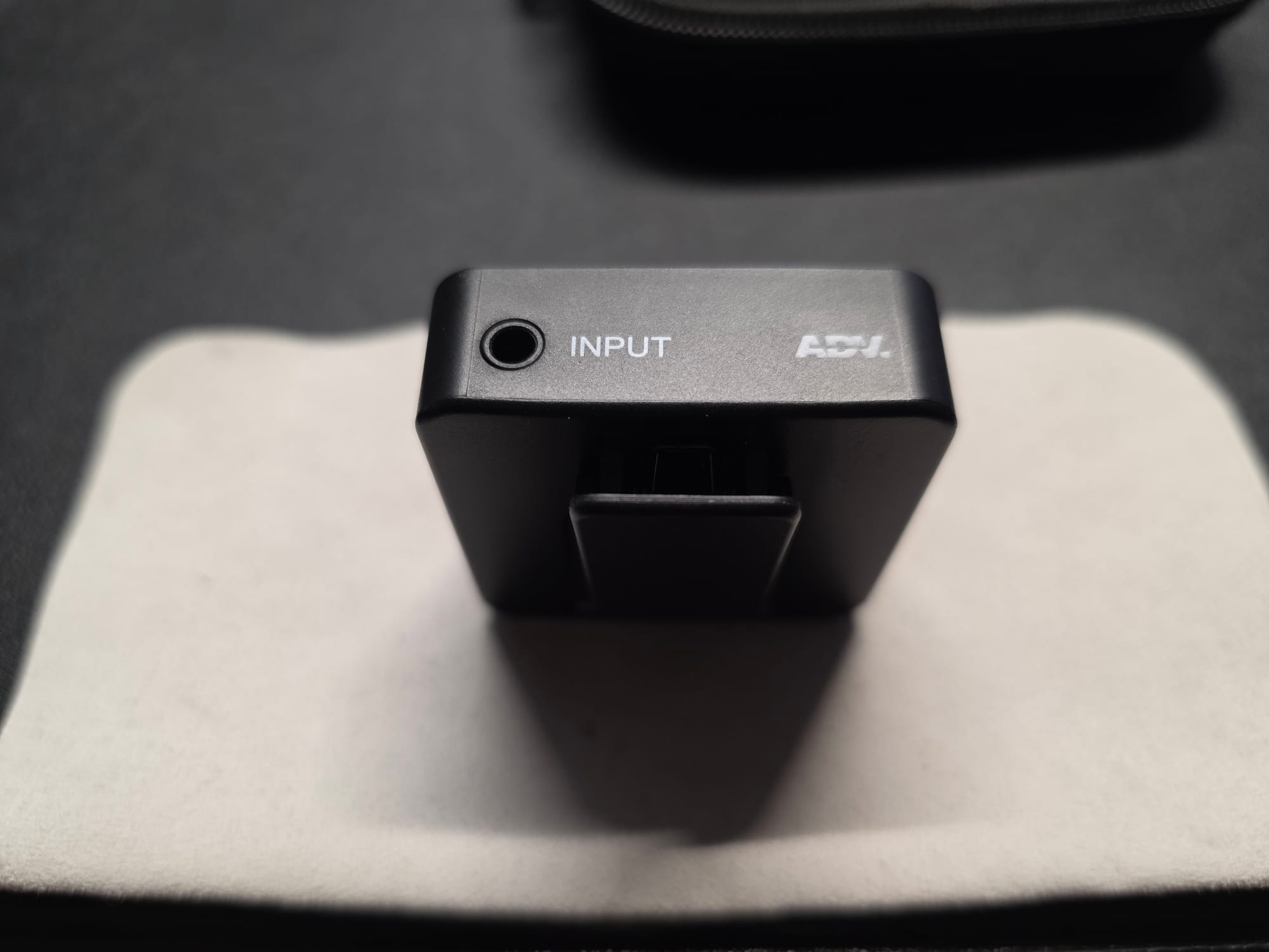 The Accessport Pro with aux jack displayed.  It is standing on its top on a white microfiber cloth on a black desk.