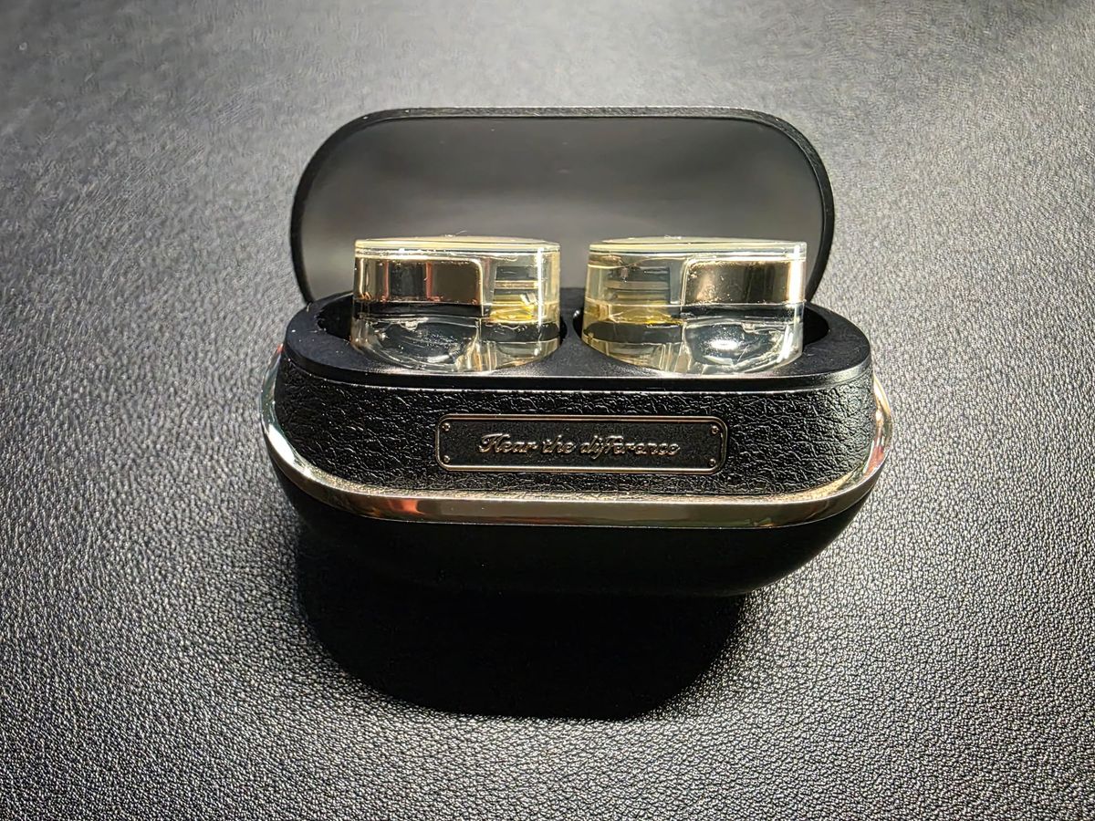 SoundPeats open in their charging case.  The case is black and the earphones are gold and transparent.