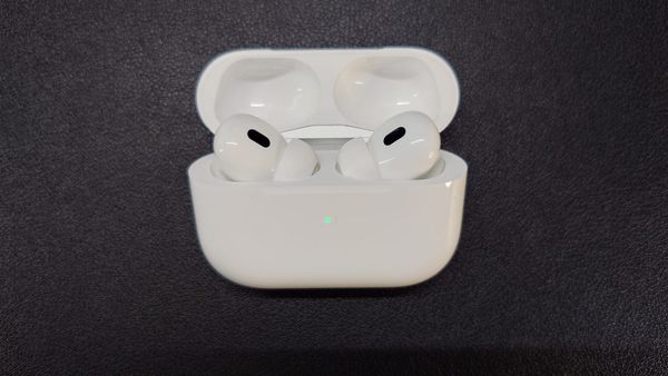 AirPods Pro 2 in their charging case, which is open, and the green light indicates high battery level