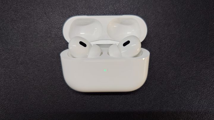 AirPods Pro 2 in their charging case, which is open, and the green light indicates high battery level