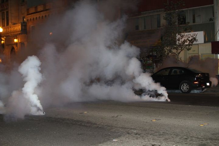 two tear gas grenades pour smoke on a street obscuring buildings