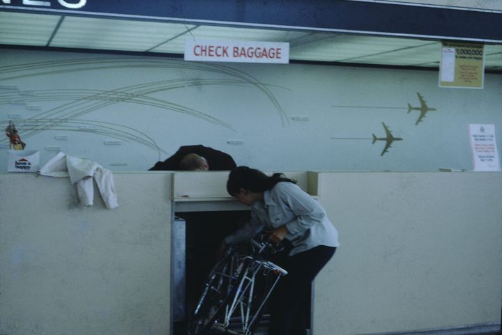 photo of someone fitting baggage into a slot in the airport check in counter