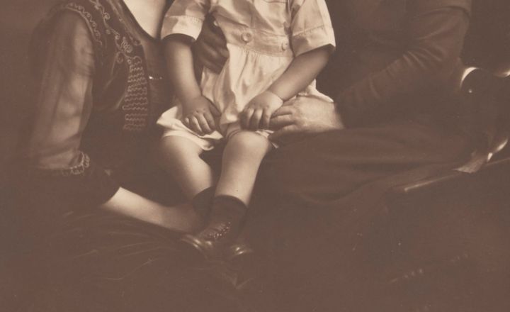 a cropped photo of a child sitting in the laps of two women