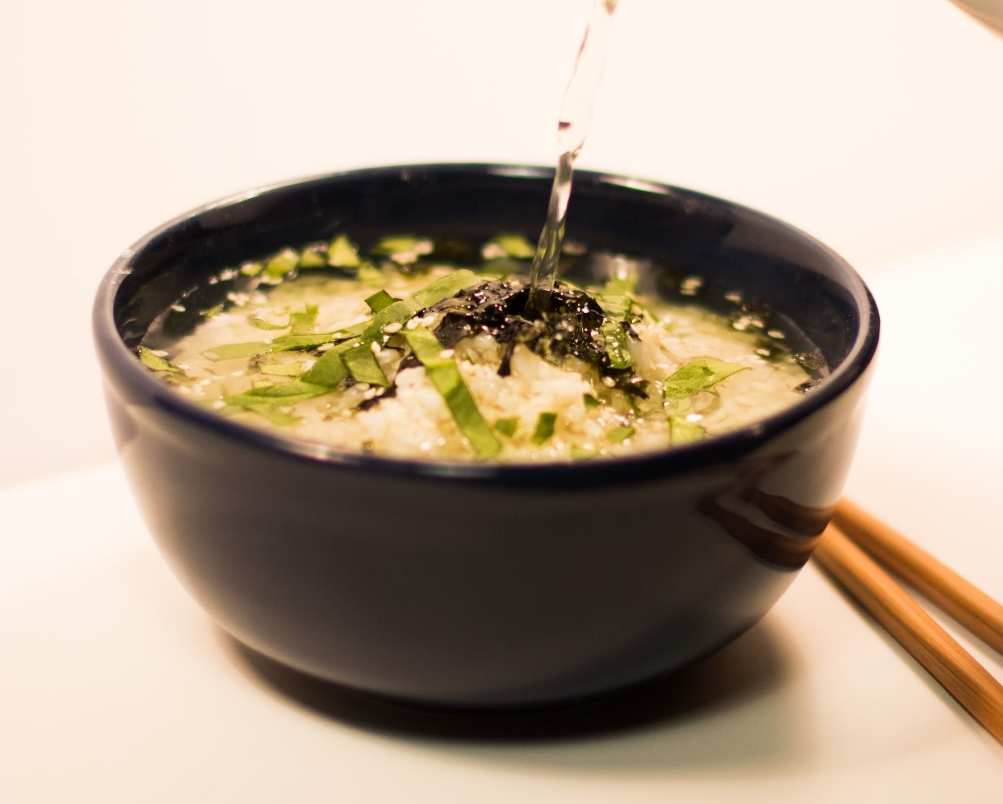 water being poured on black ceramic bowl with soup