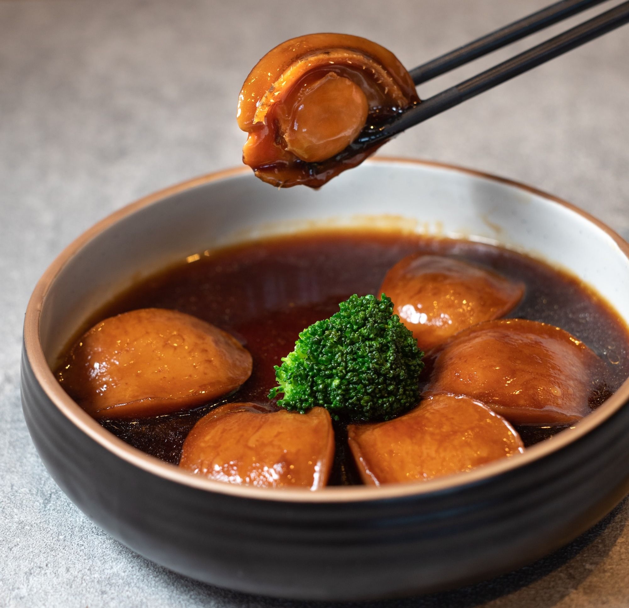 a bowl of soup with broccoli and chopsticks
