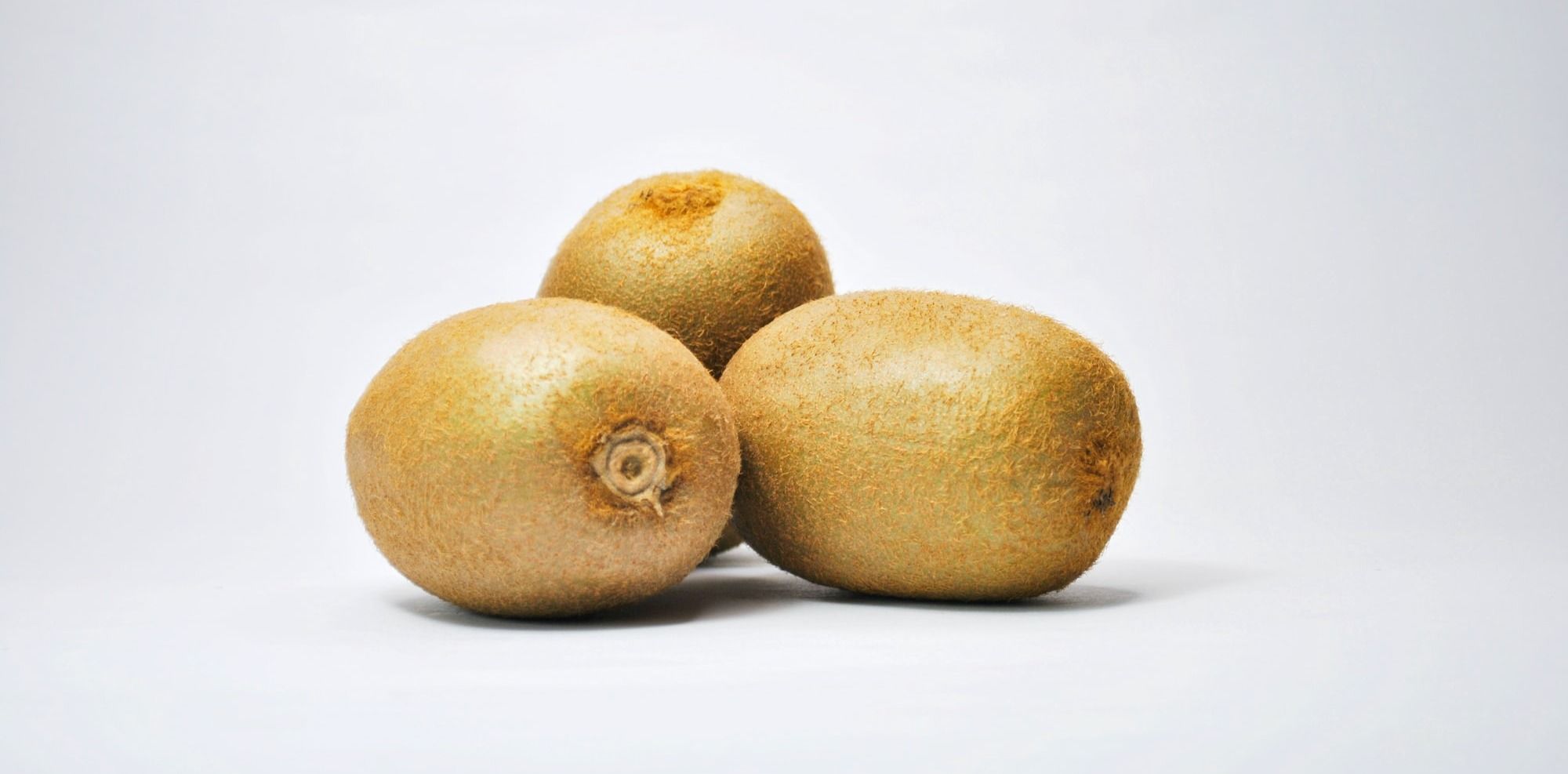 three yellow round fruits on white surface