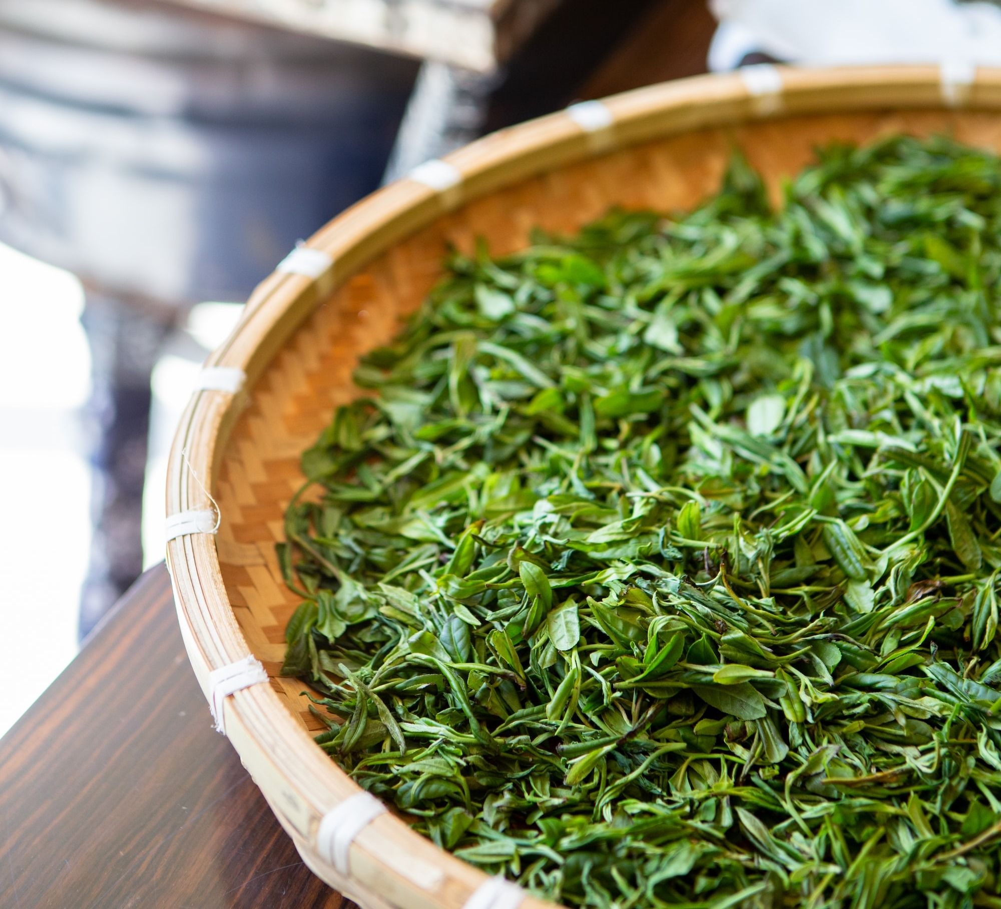 a wooden bowl filled with green leaves on top of a table