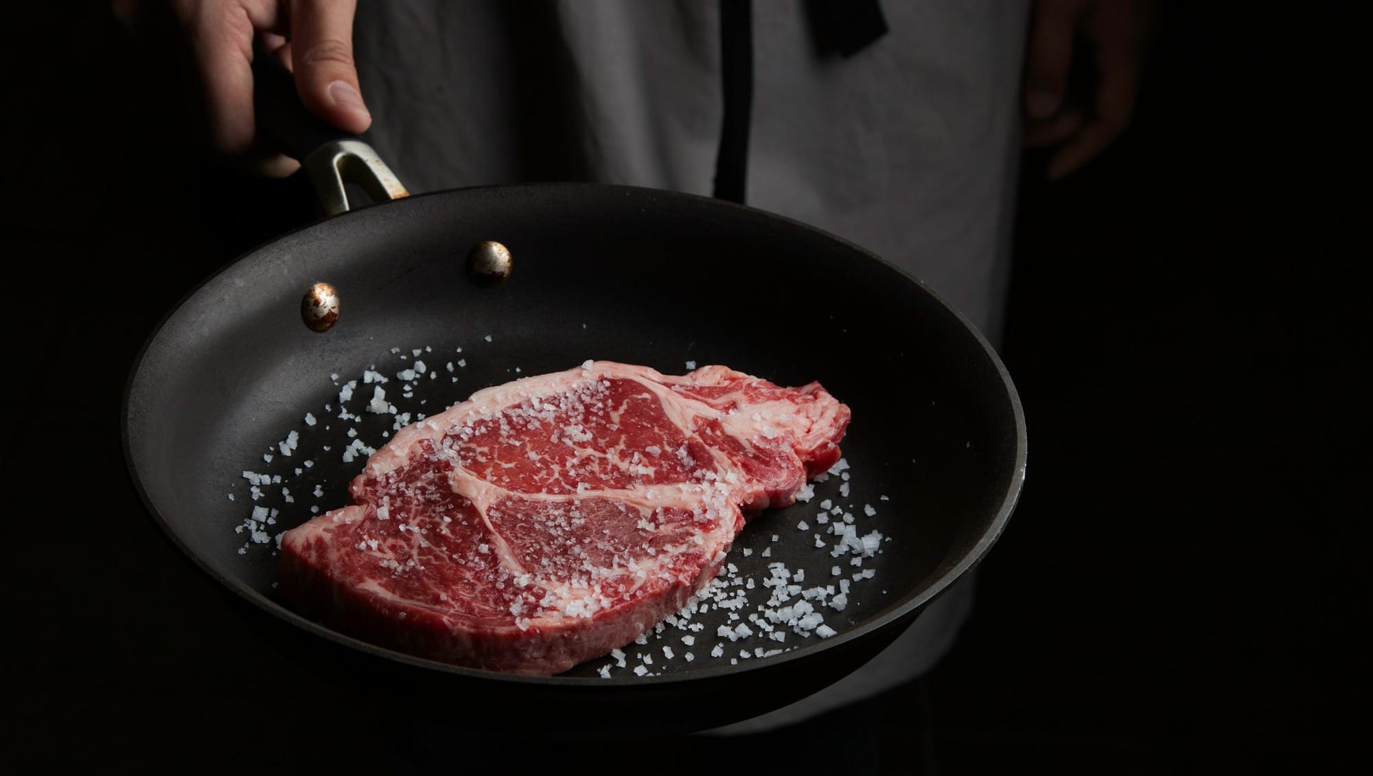 person cooking meat on black pan