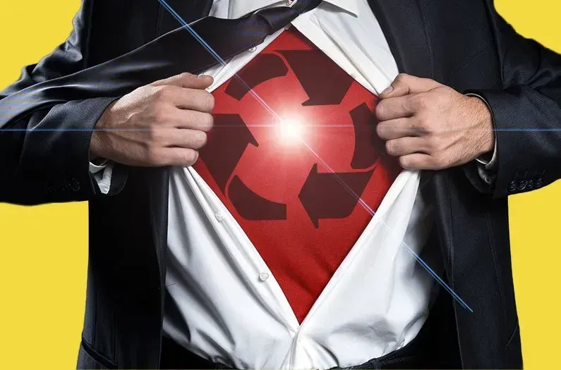 A man wearing a suit is framed to see only his chest, opens the front of his white collared button up shirt to reveal a red undershirt with a recycling symbol, symbolic of a "superhero" 