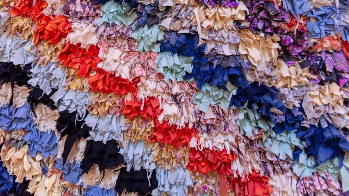 Several strips of textiles are grouped together, and hung in rows