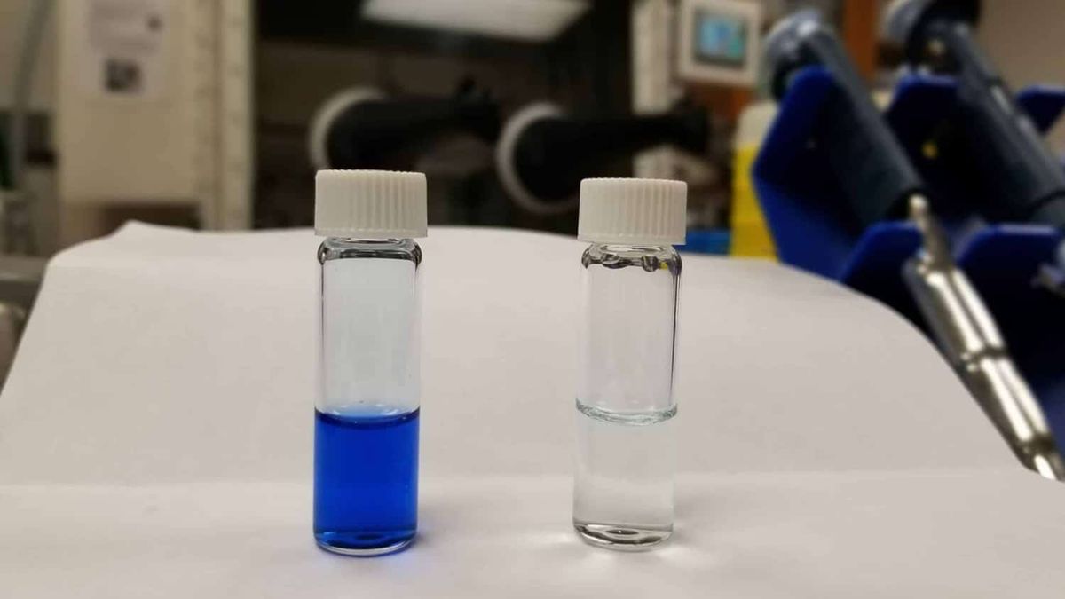 two viles of liquid stand beside eachother, one colored and one clear, implied that the clear one is a successful result of the solvent process